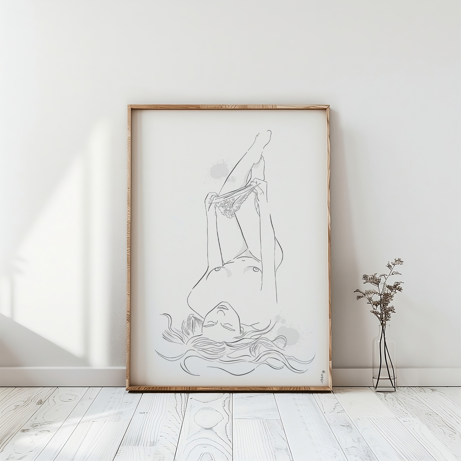 Mockup of an illustration of a nude woman undressing. This erotic art is placed in a natural color wooden frame and leans against a white wall on a white washed floor